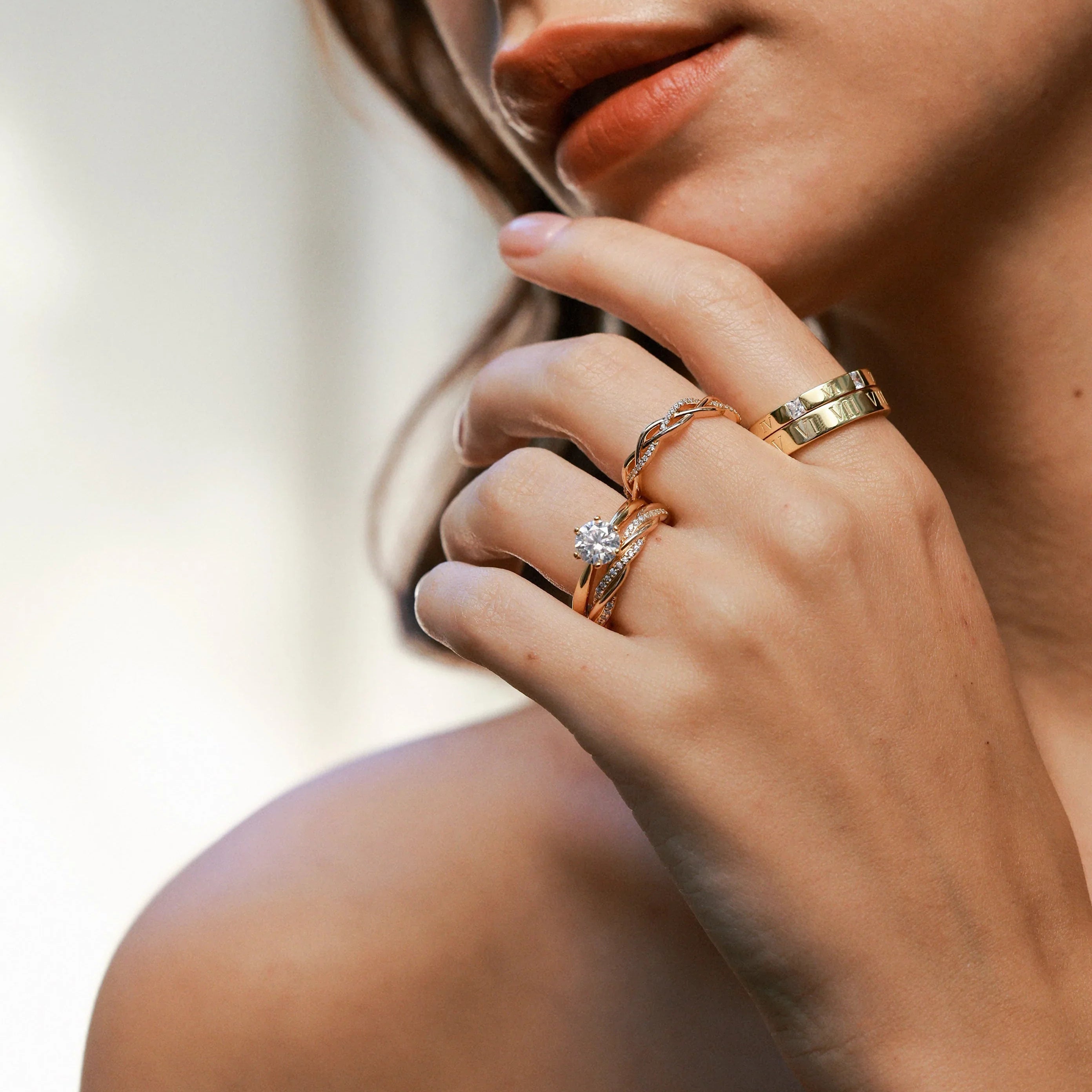 Close-up of a hand with three rings held near the chin